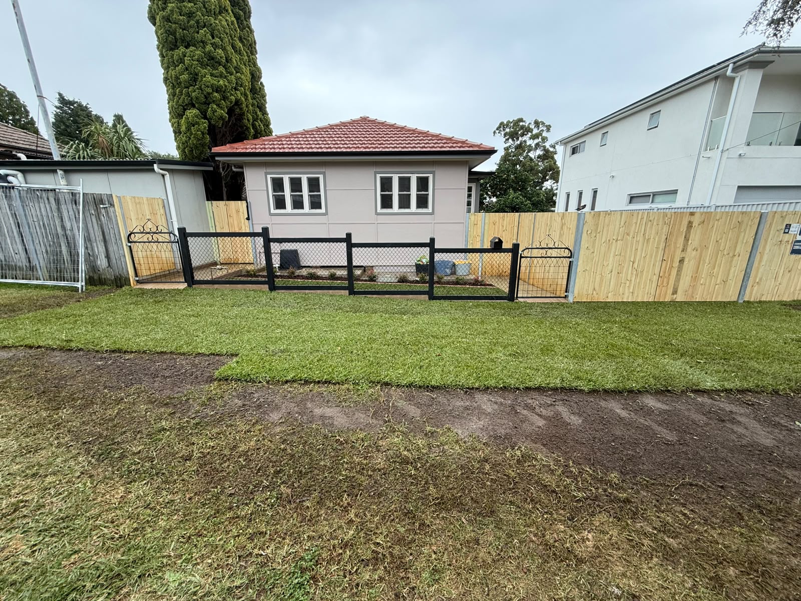 Freshly rendered and painted house exterior with new timber paling fence and freshly laid lawn
